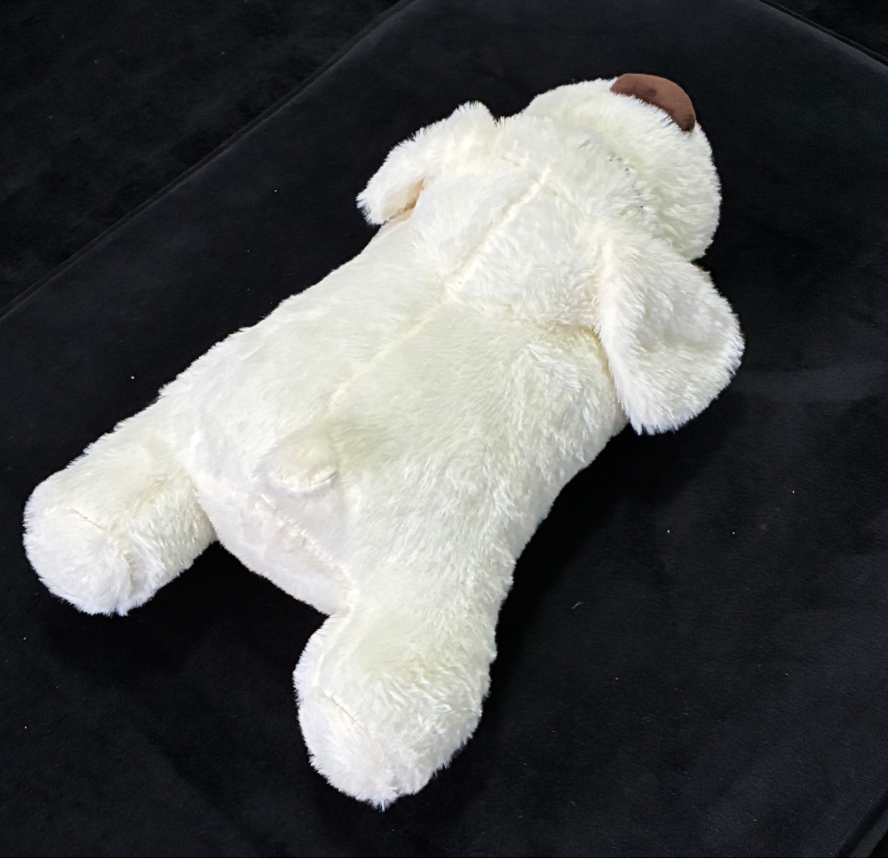 Rear view of a White plush USB heartbeat toy on a black background
